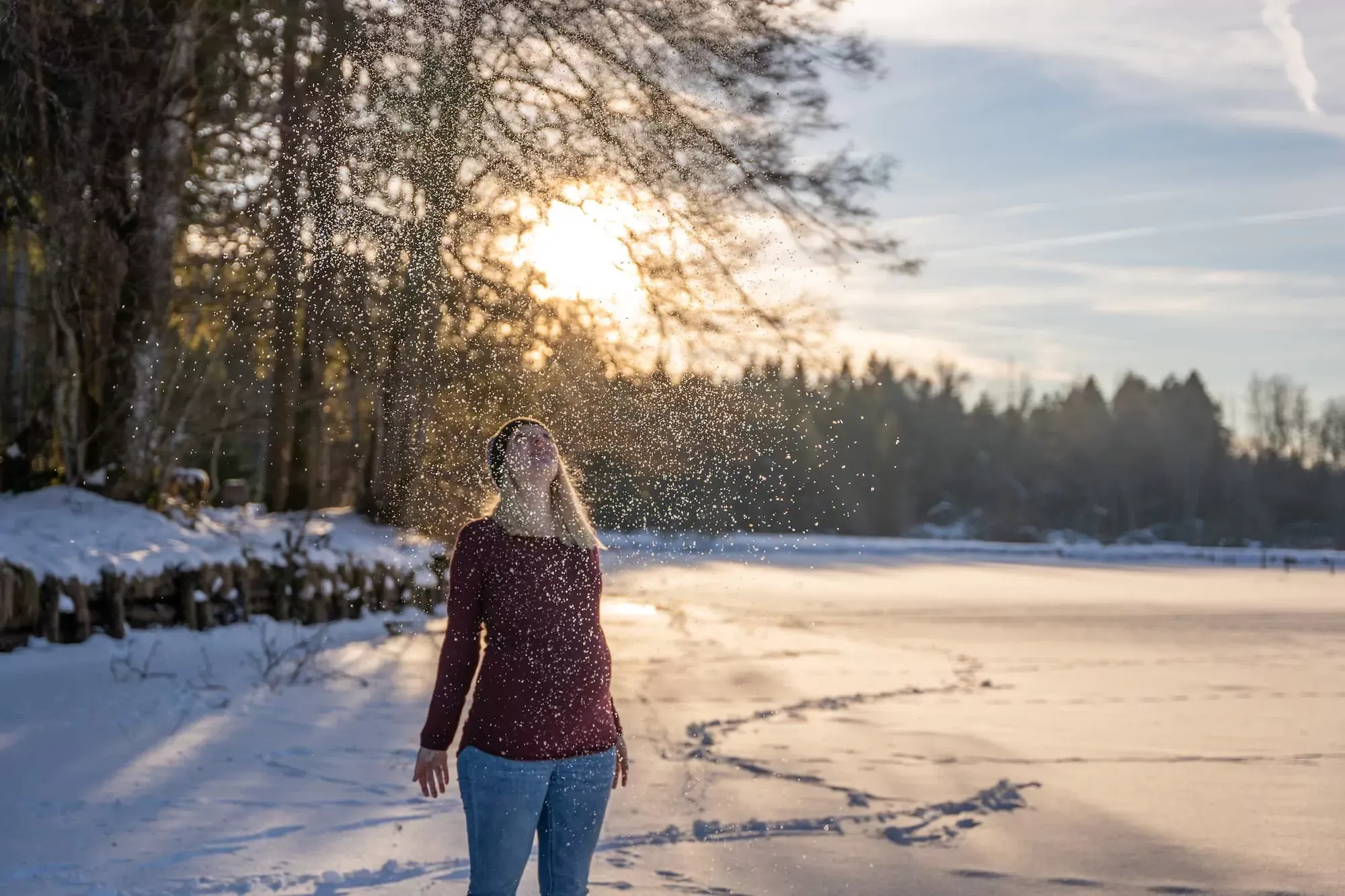 Schwangere Frau steht am Ufer eines stillen Waldsees bei Sonnenuntergang